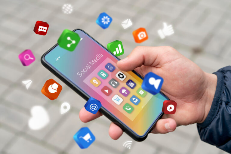 Person holding a smartphone with colorful social media app icons floating around, symbolizing digital communication, microsoft and online connectivity.