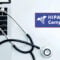 Laptop with a stethoscope next to a sign reading HIPAA Compliance, symbolizing how healthcare professionals can stay HIPAA compliant using secure technology.