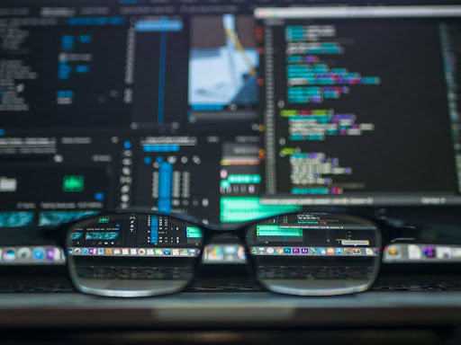 Glasses resting in front of a computer screen displaying code and data, representing cybersecurity in Southeast Idaho and advanced threat protection.